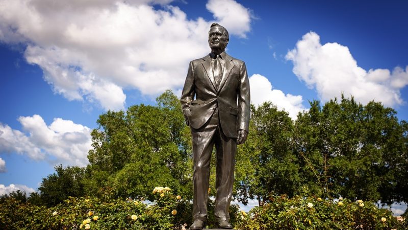 A statue of George H.W. Bush between the Bush School and the Bush Library. (Texas A&M Marketing & Communications)