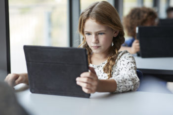 Child uses an iPad in a classroom.