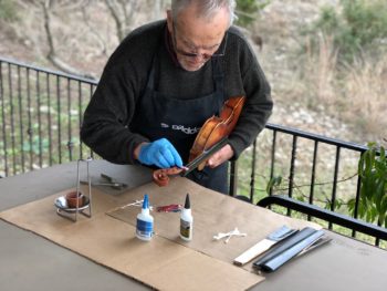Joseph Nagyvary applyies glue to a violin fingerboard.