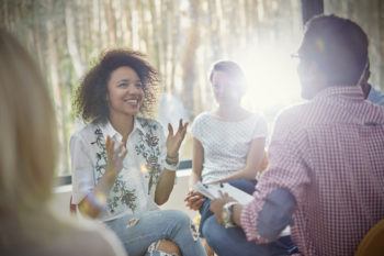 Smiling woman talking and gesturing in group therapy session