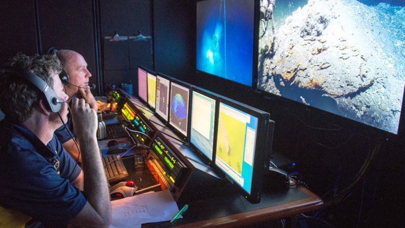Scott Sofolofsky (background) and GISR PI Chip Breier (foreground) work in the ROV control room on the E/V Nautilus