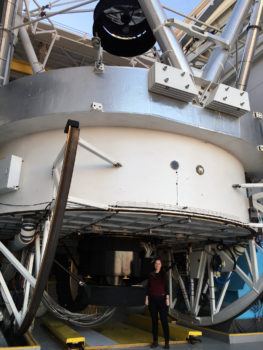 Taylor Hutchison, poses with the 6.5-meter Multiple Mirror Telescope (MMT) at the Smithsonian's Fred Lawrence Whipple Observatory in Arizona.
