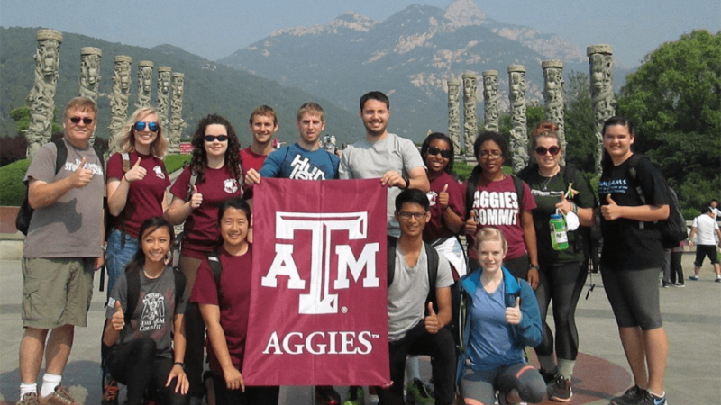 study abroad students posing with Texas A&M flag
