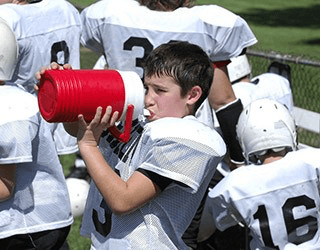 young football player drinking water