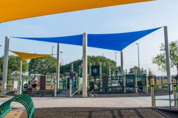 Children and parents play on a playset at the new Fun For All Playground.