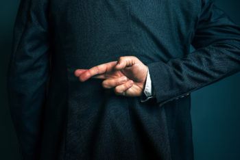 Lying and cheating businessman holding fingers crossed behind his back
