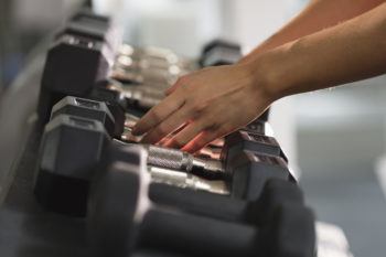 Hands of woman reaching for dumbbells