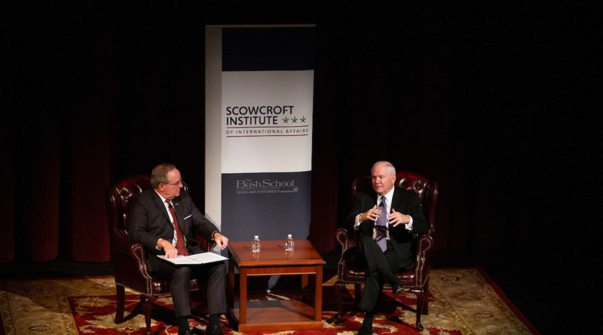 Dean Mark Welsh sits on a side next to Robert Gates
