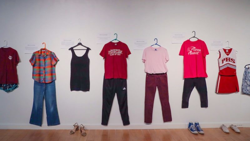 several outfits hang on a white wall