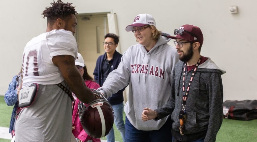 Aggie achieve students at a Texas A&M practice facility with Jimbo Fisher meeting with a football player
