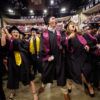 students wearing caps and gowns celebrating at graduation