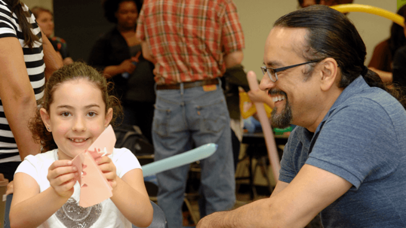 Professor of Mathematics Paulo Lima-Filho interacts with a young attendee at the Texas A&M Math Fair