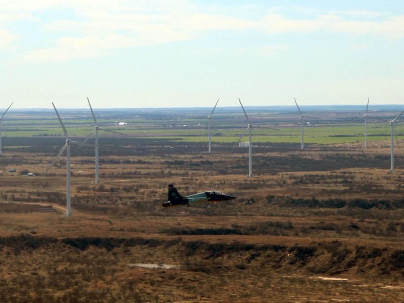 A jet flies near wind turbines in West Texas.