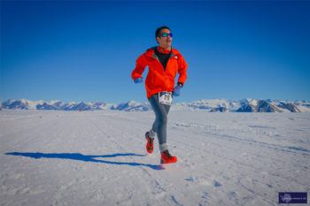 A student wearing a red jacket runs across the snow in Antarctica 