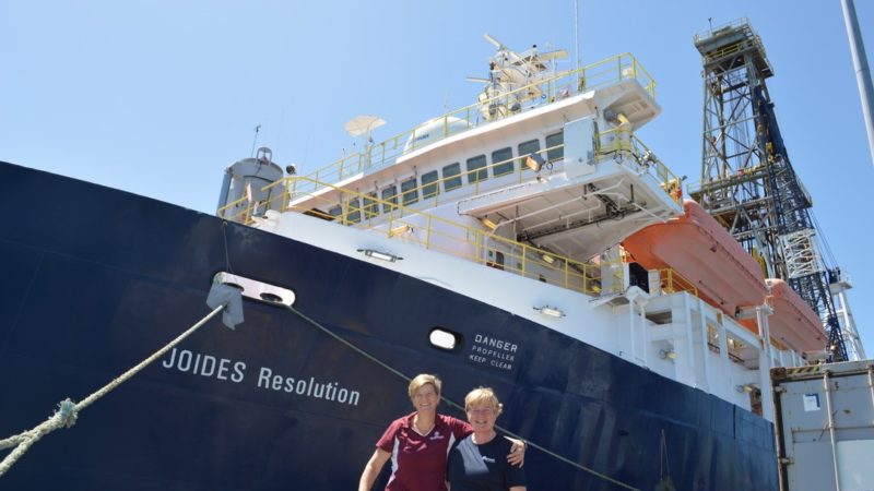 Two women stand in front of a ship