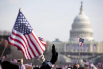 Hands of people waving flags in front of the U.S. Capitol building