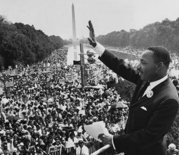 A black and white photo of Dr. King waving to the crowd at the March On Washington