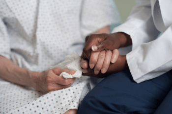 a closeup view of clasped hands of a doctor and patient
