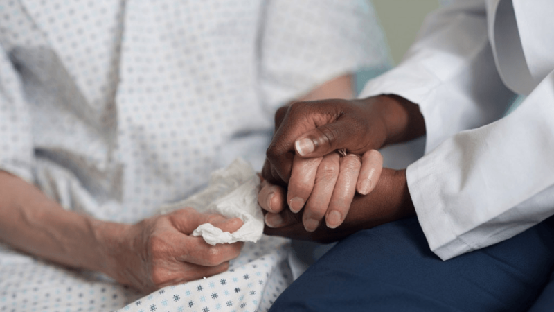 a closeup view of clasped hands of a doctor and patient