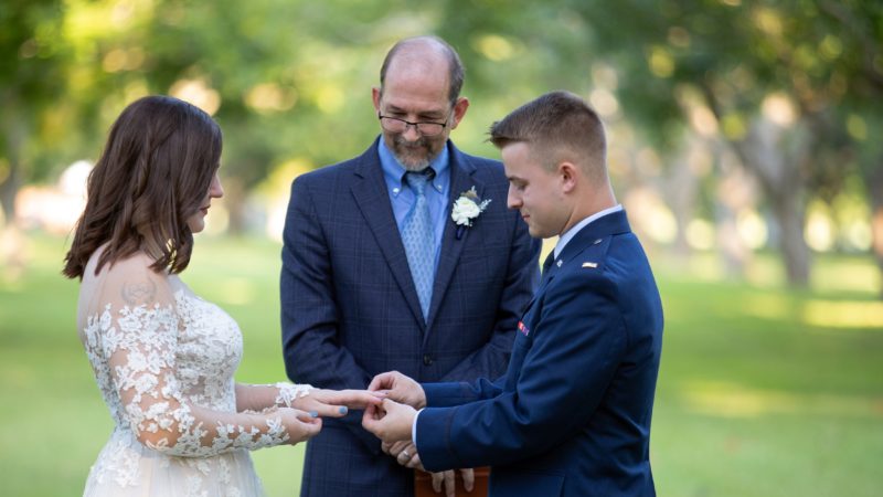 a professor standing between a bride and a groom at a wedding