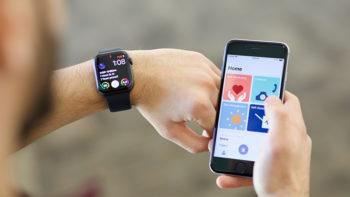 a student looks at his smartwatch while holding his cell phone next to his wrist, looking at the app
