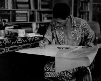 Unknown photographer, Dressed in an aloha shirt and lava-lava, Keoni works on a textile design, c. 1940s; digital image; © Keoni Collection.