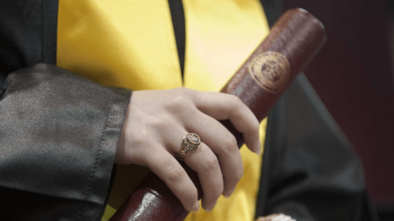a new graduate wearing an aggie ring and holding a diploma