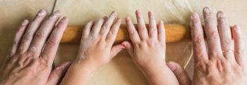 child's hands and adult hands on a rolling pin