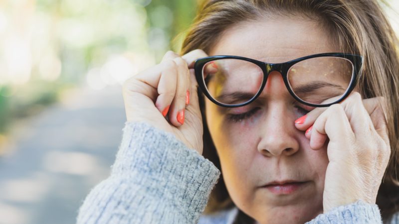 Woman rubbing her eye outdoors