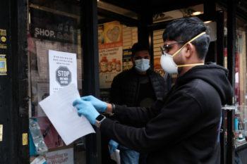 Men wearing protective masks put up signs outside of a pharmacy forbidding those who are sick from entering