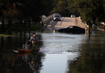A resident pulls personal belongings on a kayak as he wades through floodwaters