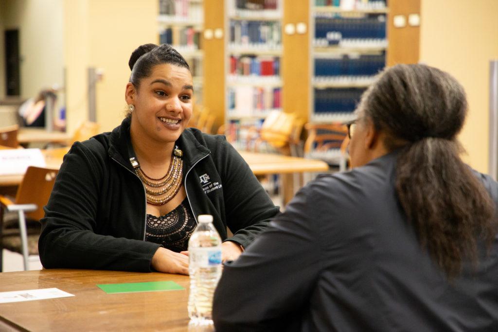 Two women sitting across a table from one another talking during the Human Library event