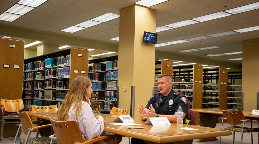 A woman sitting across from a University Police Officer having a conversation.