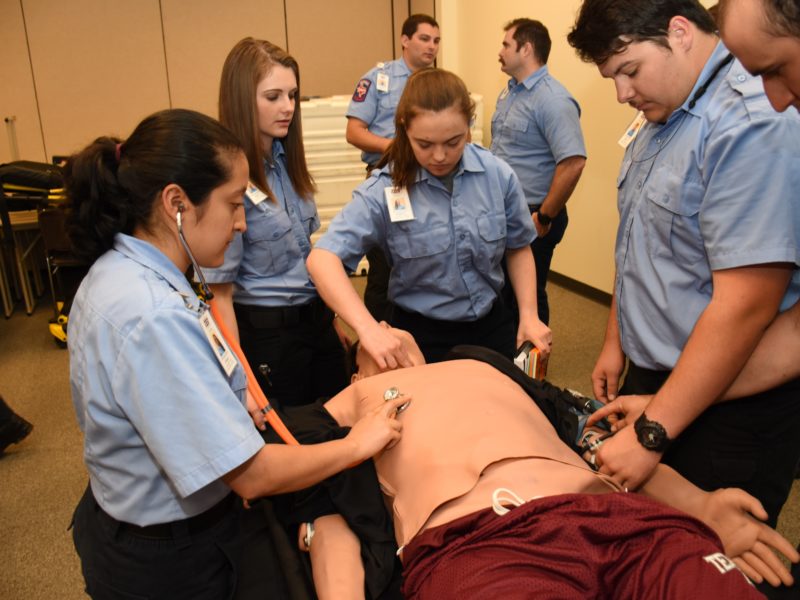 first responders in unison surrounding a manneqwuin, taking its vitals