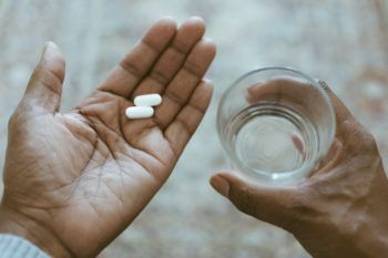 Close-Up View of Hands Holding Pills and Water
