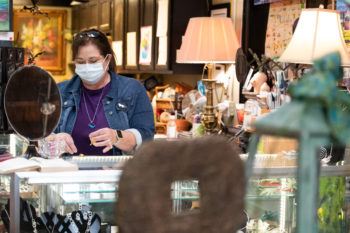 woman wearing a face mask behind counter at antique store