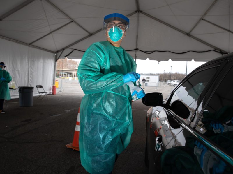 doctor in protective equipment preparing to test a patient in their care at a drive-thru testing site