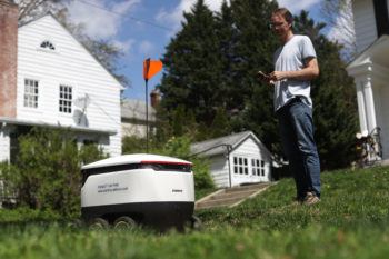 resident standing outside house watching robot leave