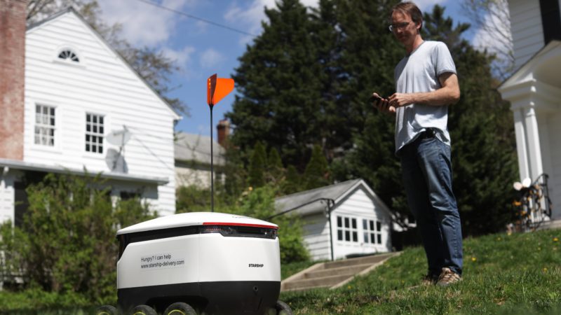 resident standing outside house watching robot leave