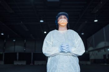 a nurse in protective gear stands for a portrait at a drive through testing center