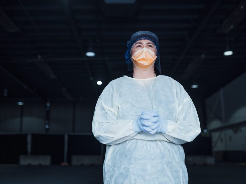 a nurse in protective gear stands for a portrait at a drive through testing center