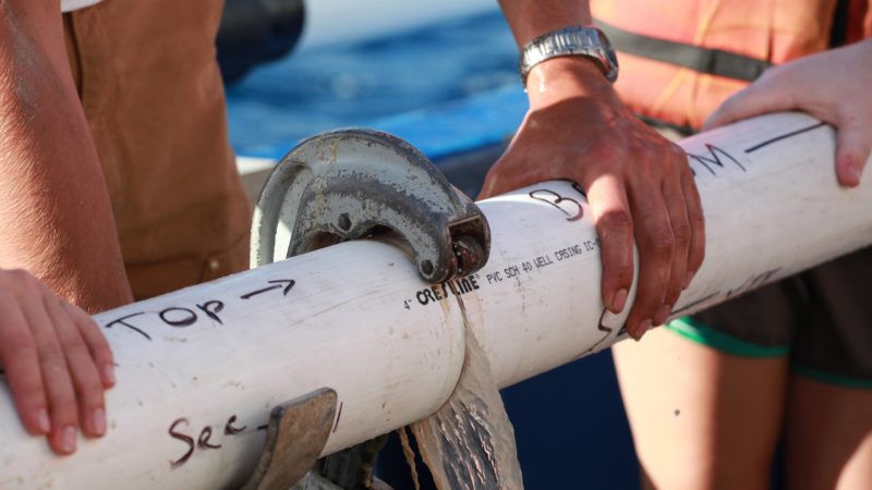 hands holding sediment core on boat