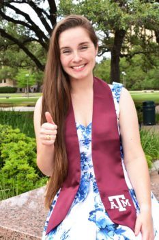 a photo of Isolde Parrish in her graduation sash giving the Gig 'em thumbs up