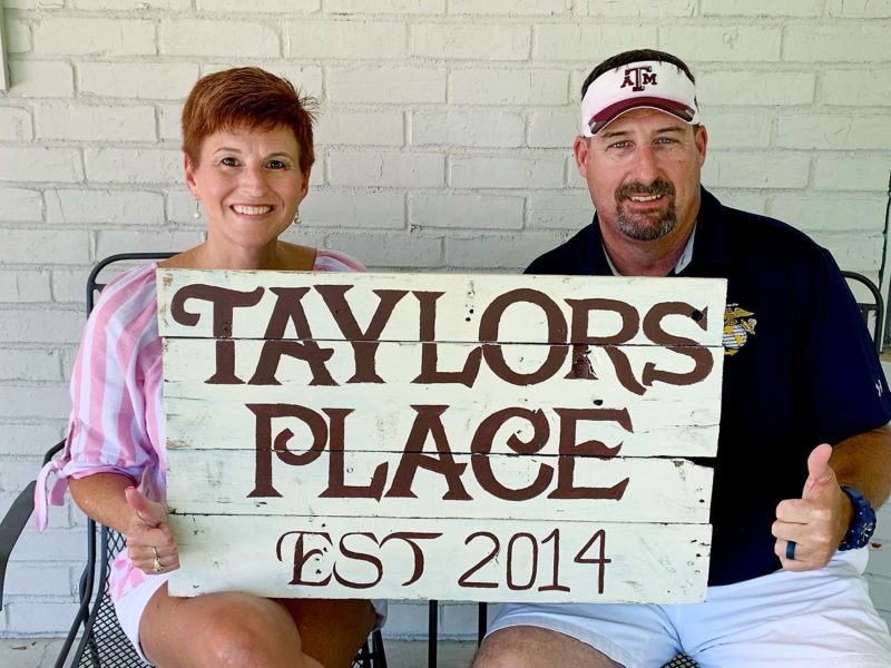 gillespies sitting on porch holding taylors place sign