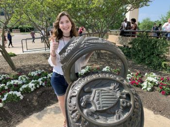Sarah Venesky posting next to aggie ring sculpture on ring day
