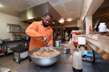 black businesses owner korey thomas stands at a counter in a restaurant kitchen stirring ingredients in a bowl