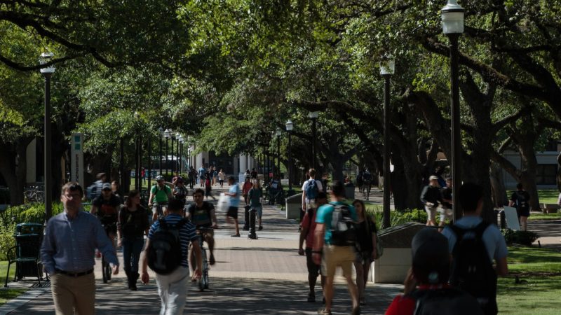 students walking in shaded area of campus between campus