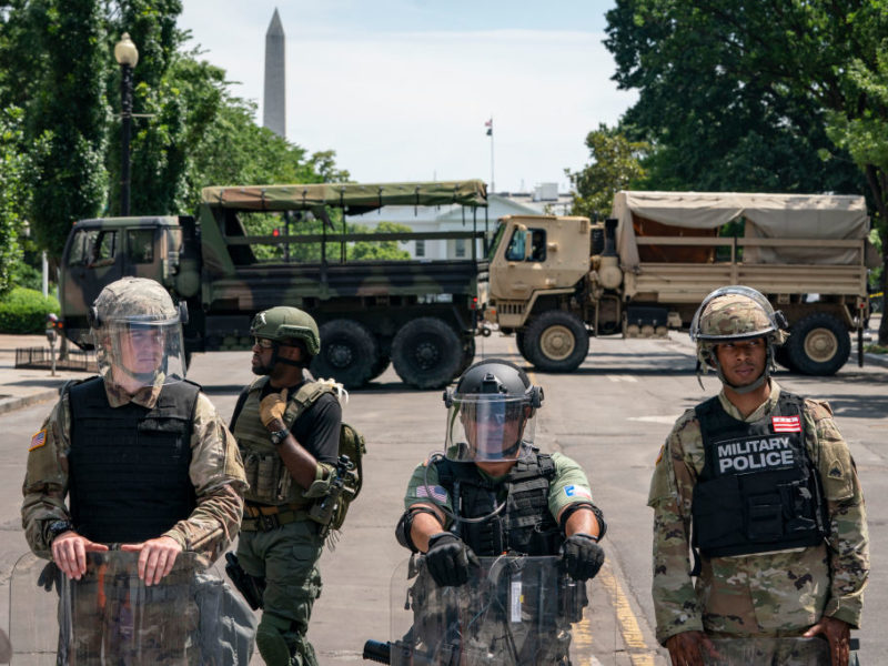 police officers and national guard vehicles block a street with the white house in the background