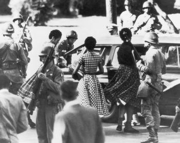 blakc and white hoto of black students with military escorts outside a school