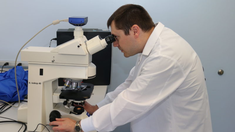 photo of andrew laurence looking through microscope